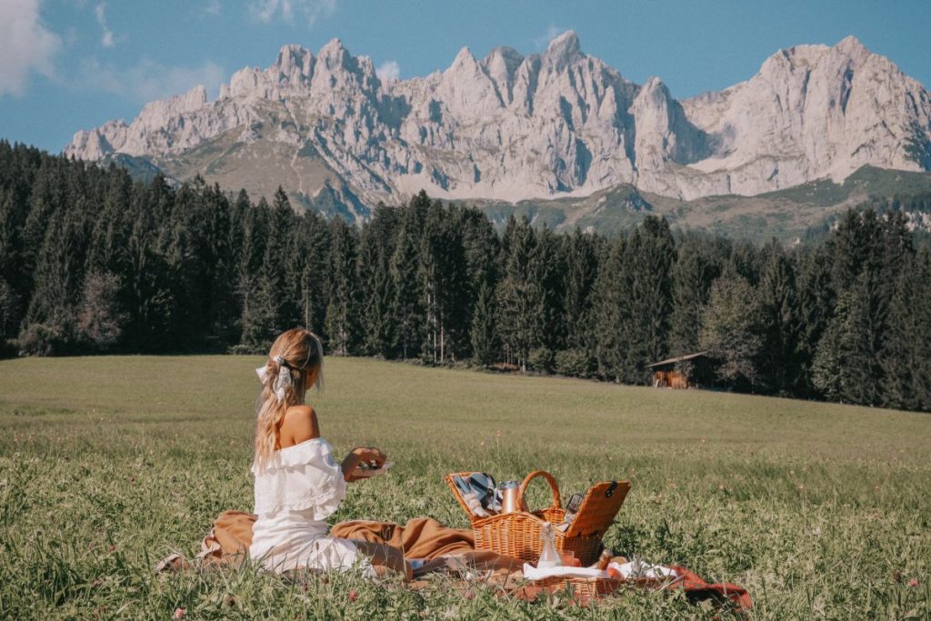 A lady enjoying a picnic while looking out over the Alps at Stanglwirt in Austria